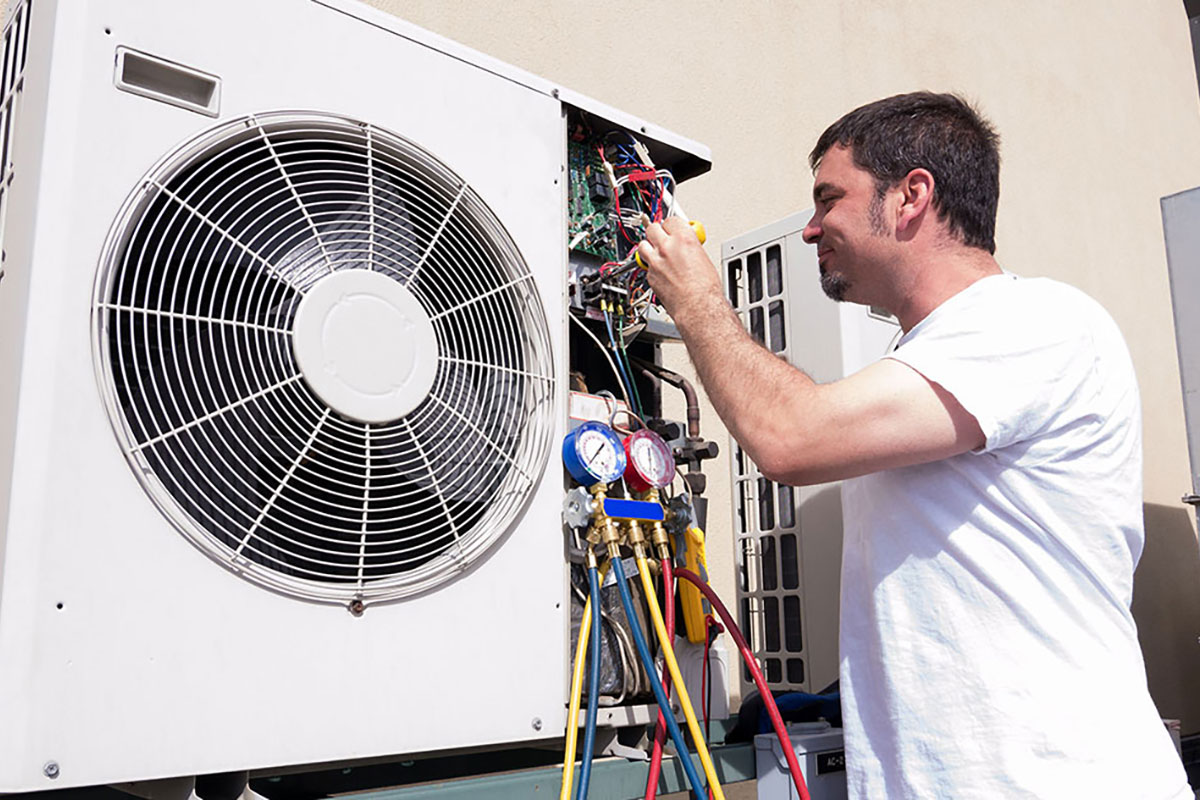 Comfortec technician inspecting an outdoor AC unit during an AC repair vs replace visit in Spirit Lake, Iowa